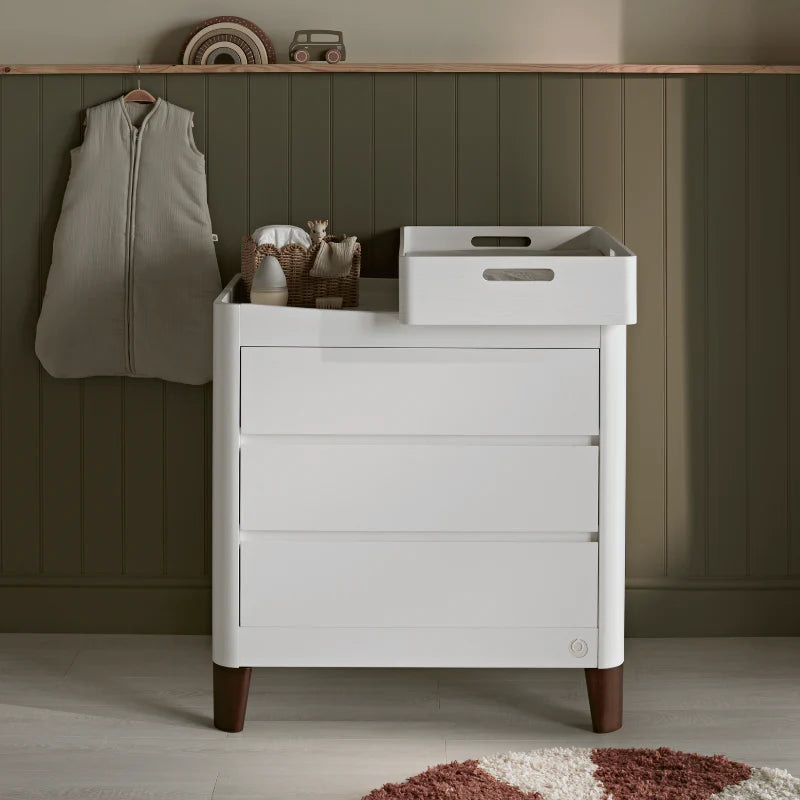White Gaia Baby Serena Dresser with a changing station on top in a nursery with green panelled walls