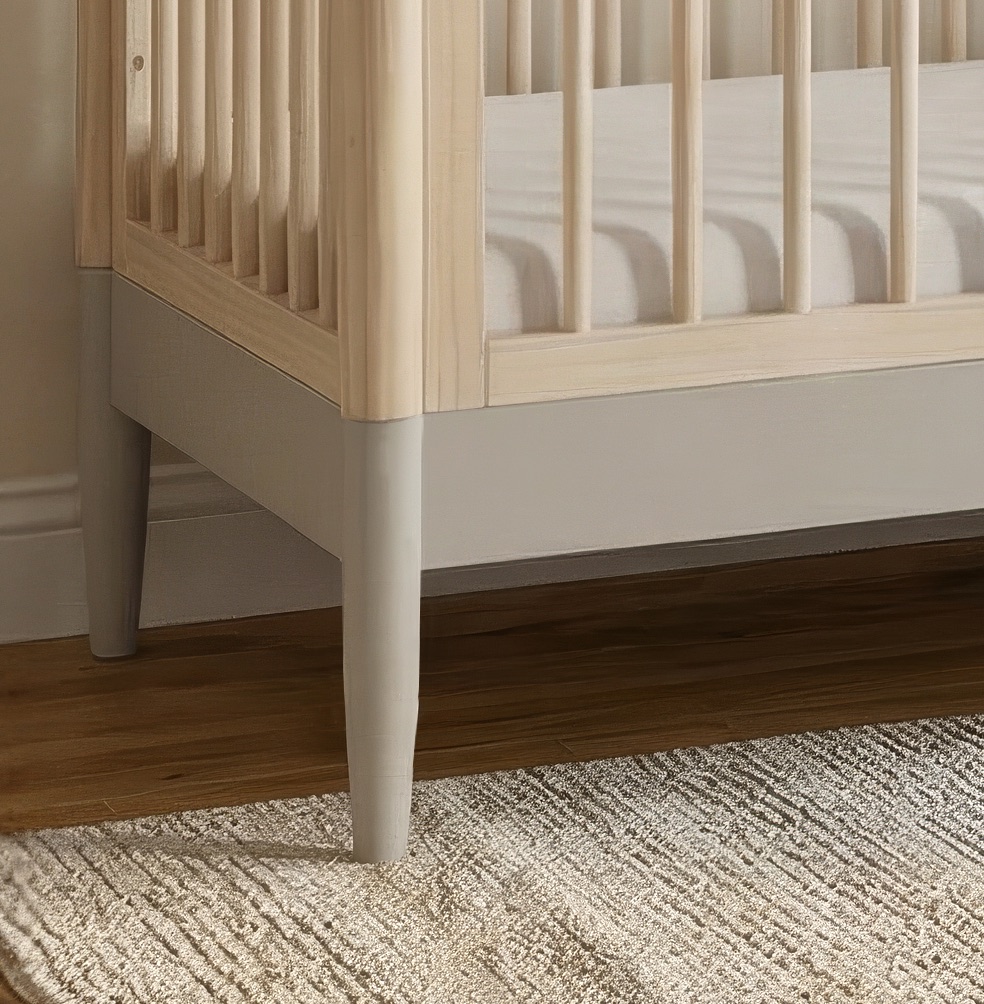 Close view of a Gaia Baby Eos cot bed with its mattress fitted, in a nursery with a woven rug