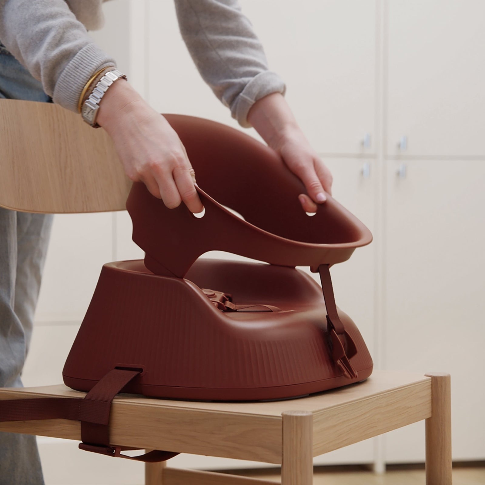 Adult fitting the seat support onto a Mahogany Red Hannie strapped to a timber dining chair