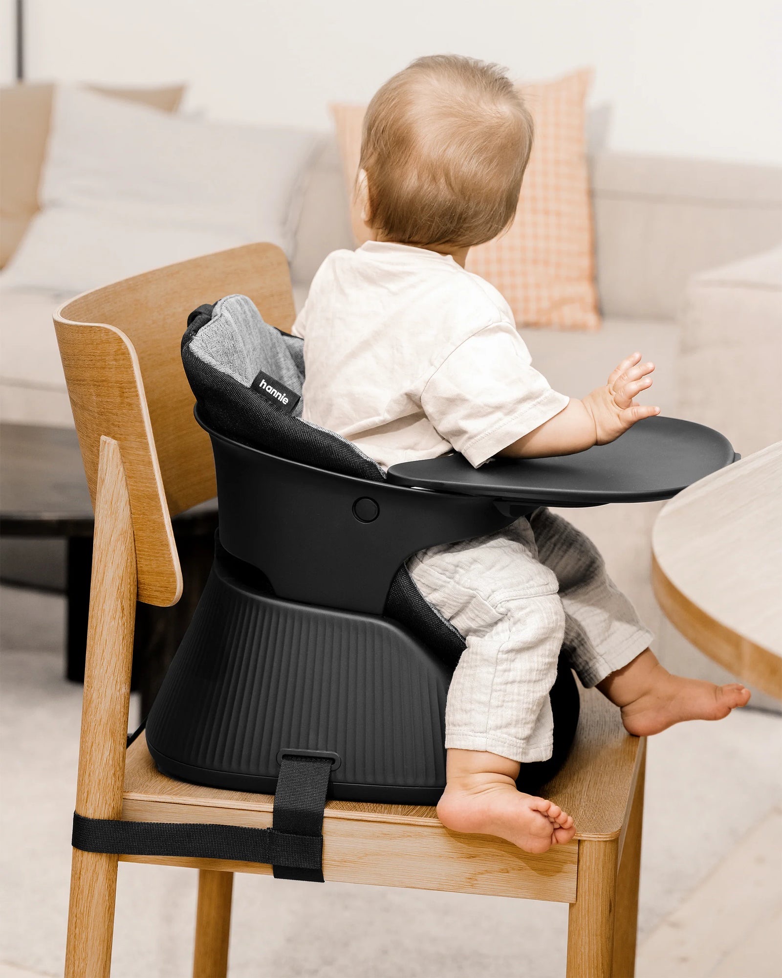 Baby sitting in a Charcoal Black Hannie in Baby Chair mode with the tray, attached to a timber dining chair