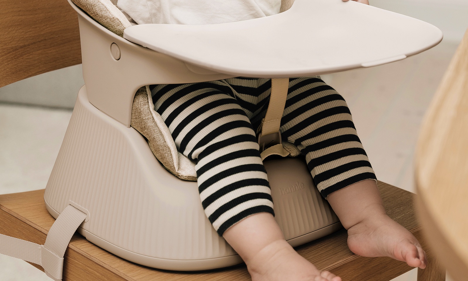 Baby secured with the 3-point harness in a White Sand Hannie with the cushion and tray fitted