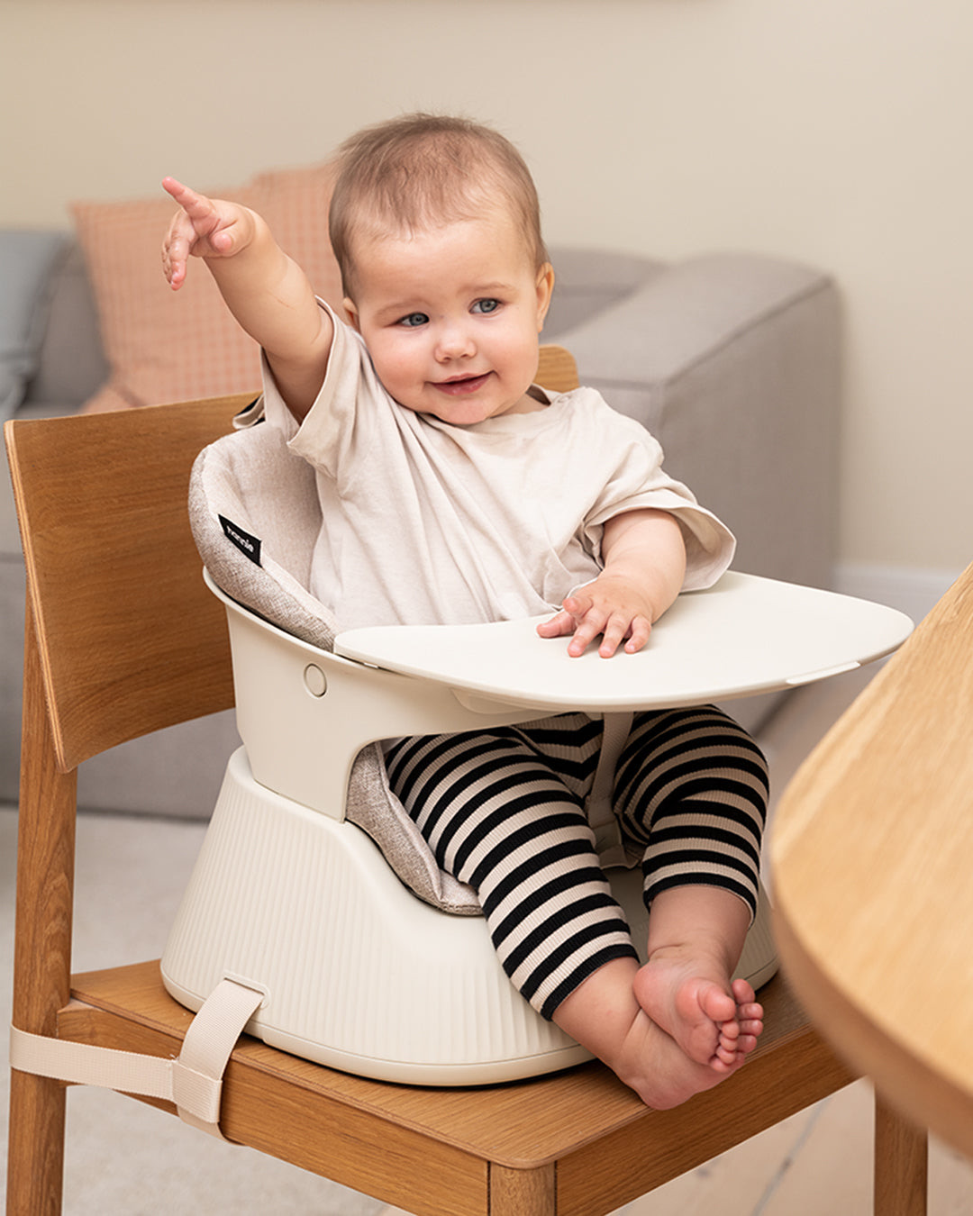 Smiling baby in a White Sand Hannie with a hand resting on the tray