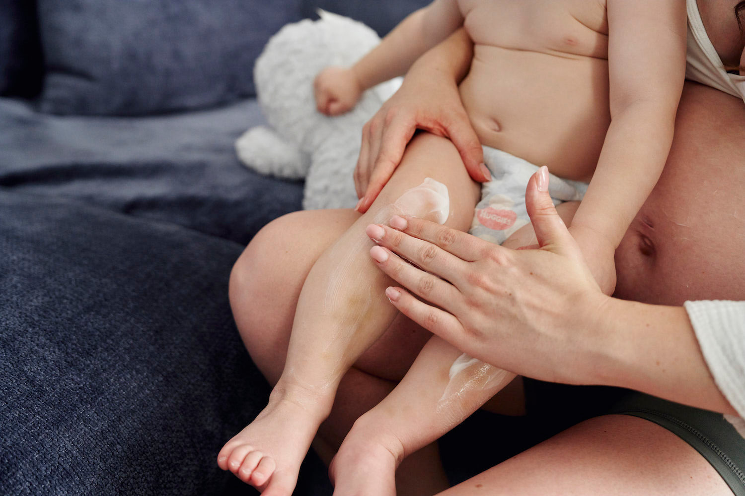 A parent massaging a toddler's leg while the child sits on their lap.