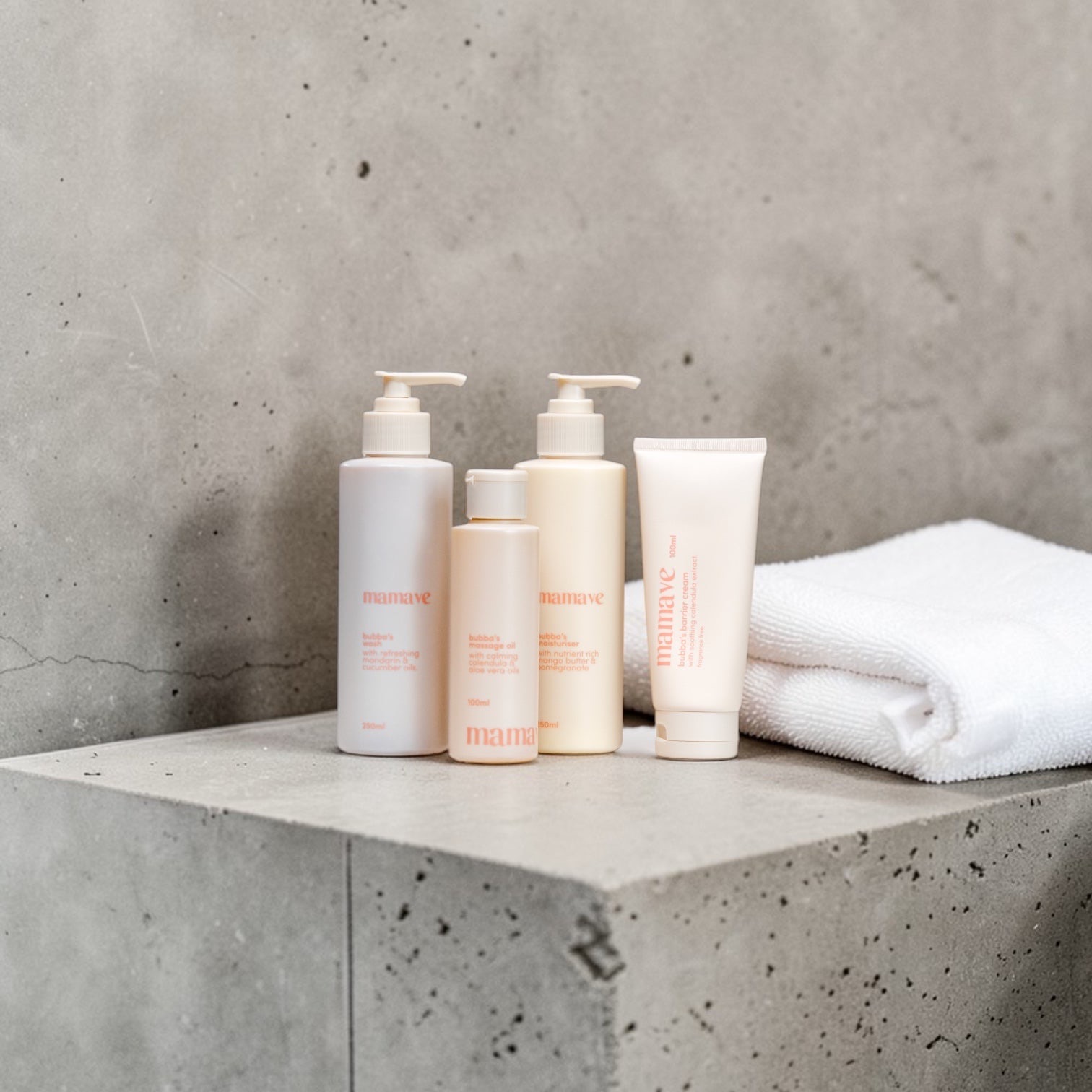 Mamave Bubba range bottles and a tube on a concrete bathroom ledge beside a folded white towel.