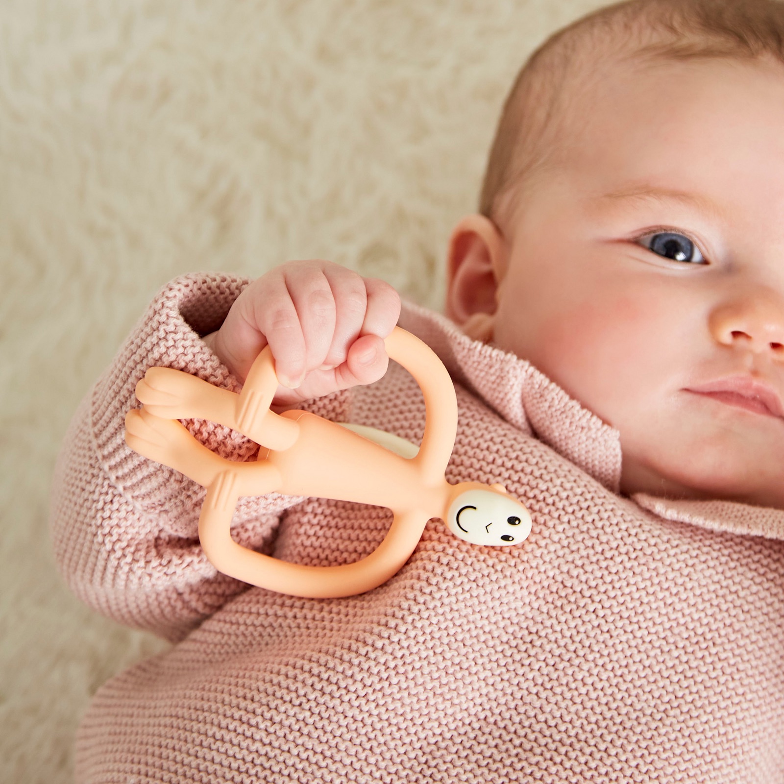 Baby holding a peach Matchstick Monkey Original teether.