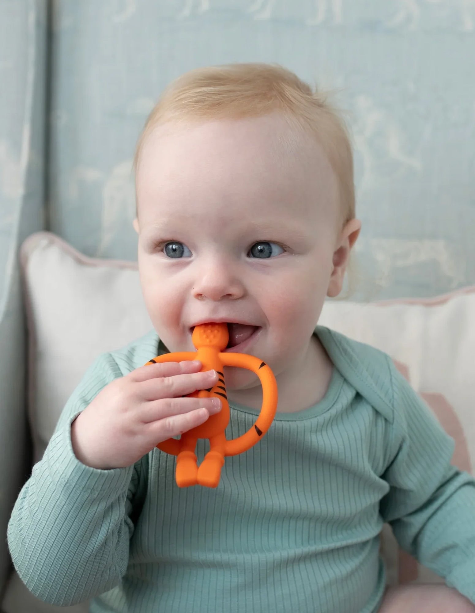 Baby chewing an orange Matchstick Monkey Tiger Teether.