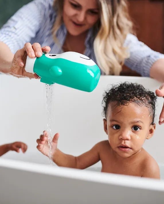 Parent pouring water from the Matchstick Monkey Hair Rinser at bath time while a toddler sits in the bath.