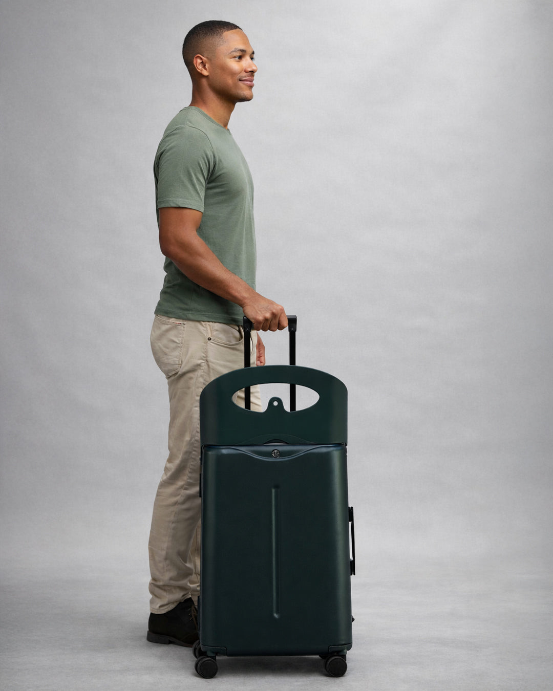 Man standing beside a Forest Green MiaMily Check In suitcase with the seat raised
