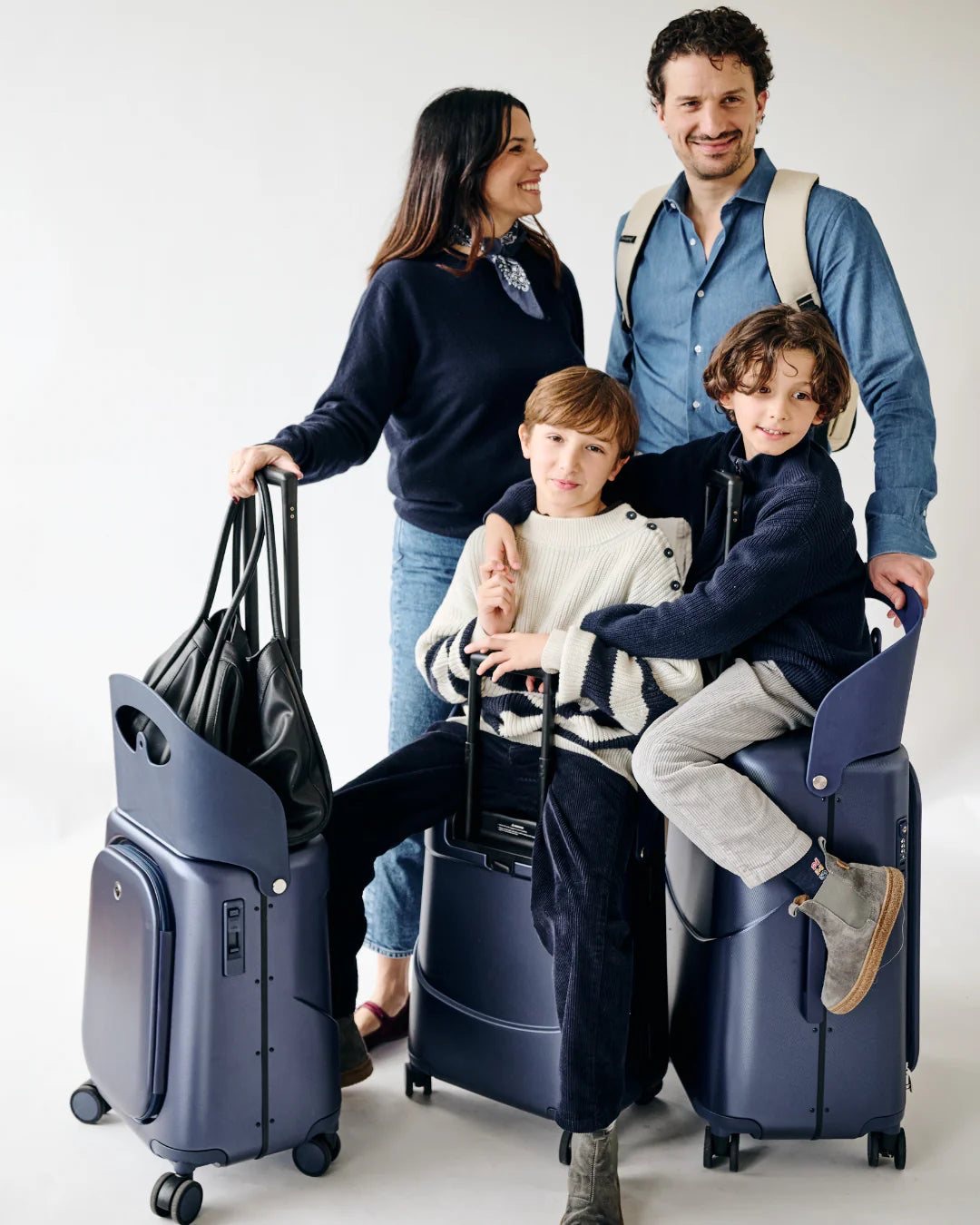 Family with navy MiaMily Plus suitcases and a bag hung on the seat hook