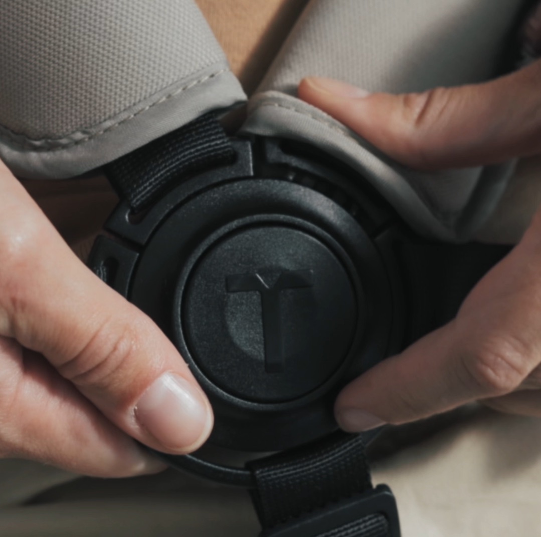Close-up of hands fastening the buckle of a smarTrike 5-point harness.