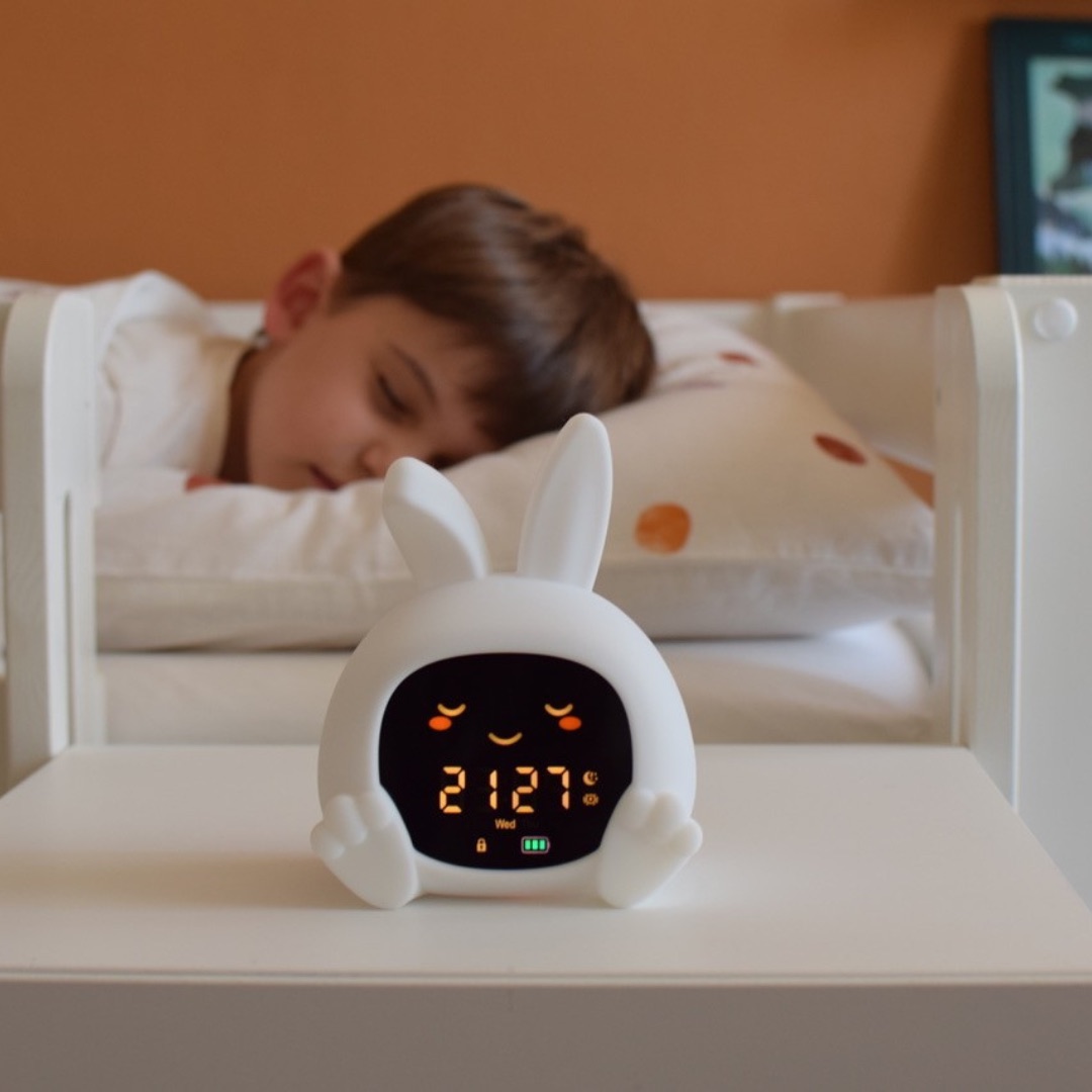 Sarah the Rabbit sleep trainer clock on a bedside table next to a sleeping child.