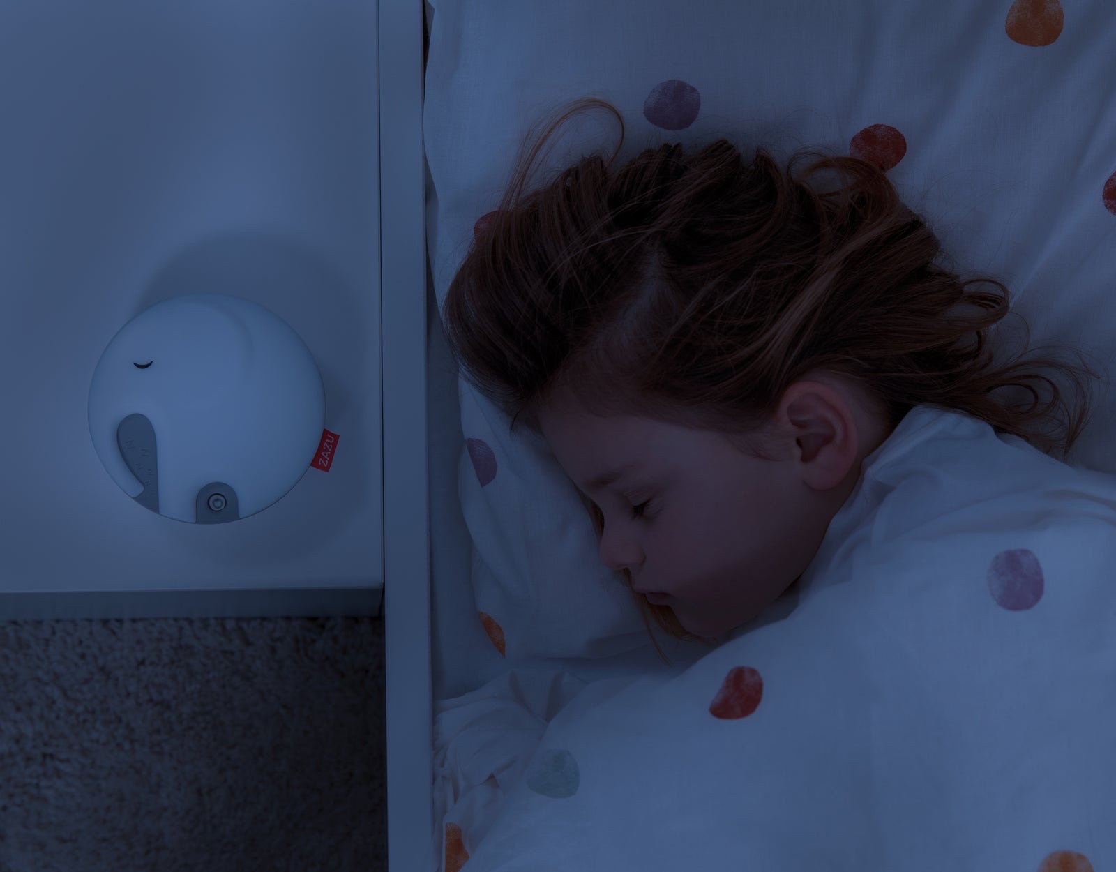 Emmy the Elephant on a bedside shelf next to a sleeping child.