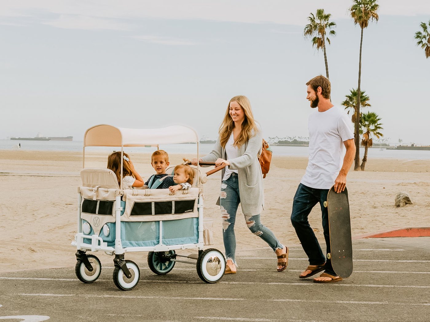 A family walking a WonderFold wagon at the beach