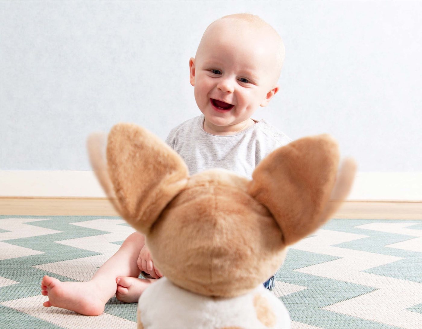 A laughing baby with a Zazu soft toy