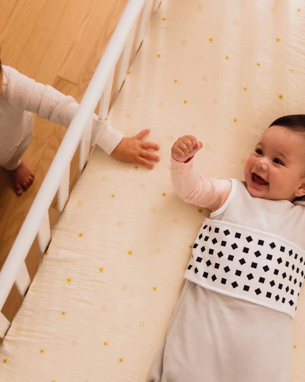 A smiling baby lying in a cot